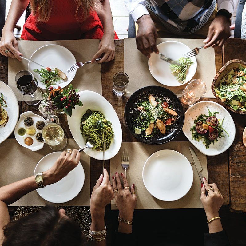 4 people at a dinner table serving themselves food