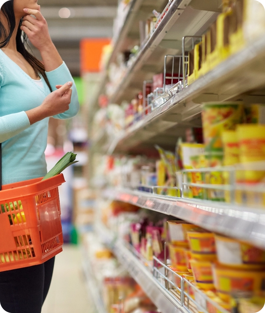 A shopper with a basket in a grocery aisle